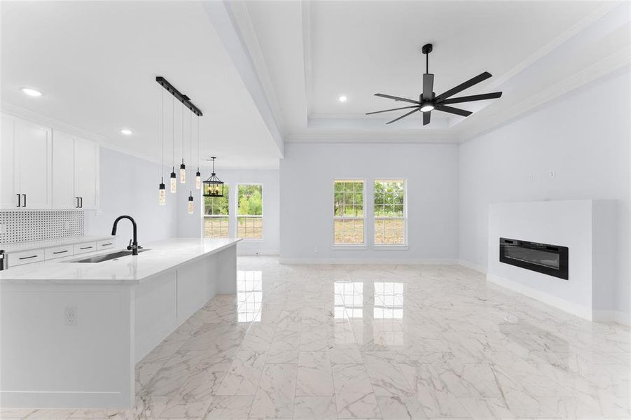 Kitchen with white cabinets, decorative light fixtures, sink, a spacious island, and ceiling fan