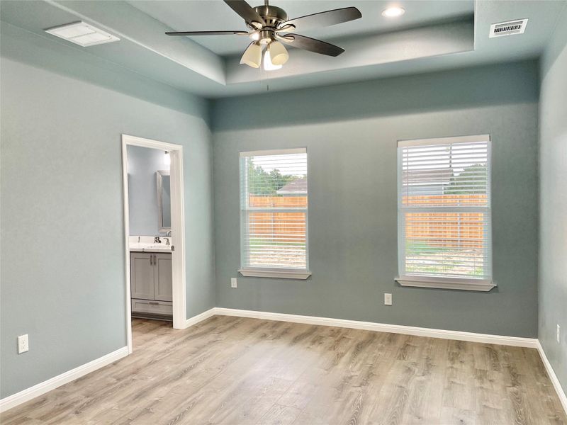 A quiet retreat with a graceful tray ceiling and wood-look flooring.