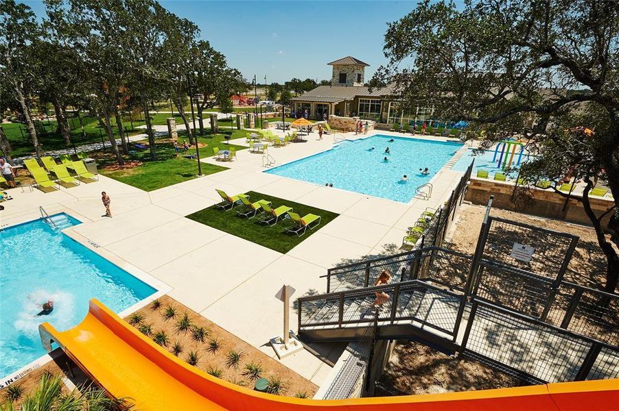 The community features a large swimming pool with a water slide, a separate smaller pool, and a splash pad area