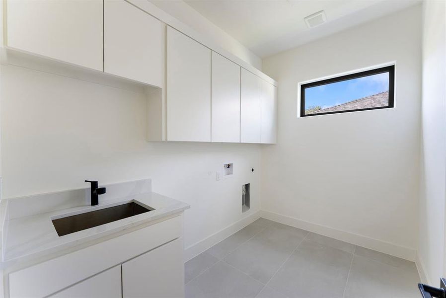 Washroom featuring light tile patterned floors, hookup for an electric dryer, cabinet space, and washer hookup Washroom featuring light tile patterned floors, hookup for an electric dryer, cabinet space, and washer hookup