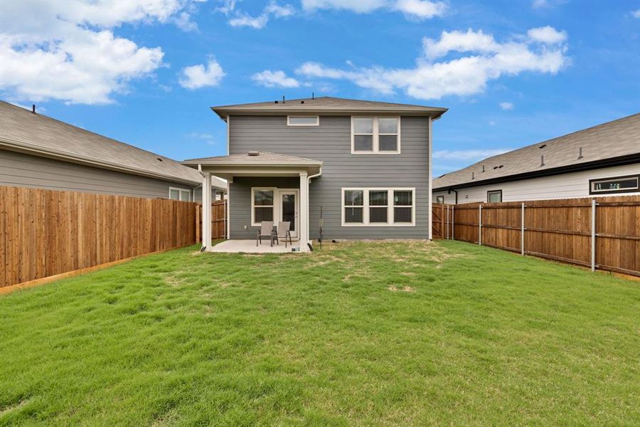 The property features a spacious backyard with a well-maintained lawn and a private wooden fence