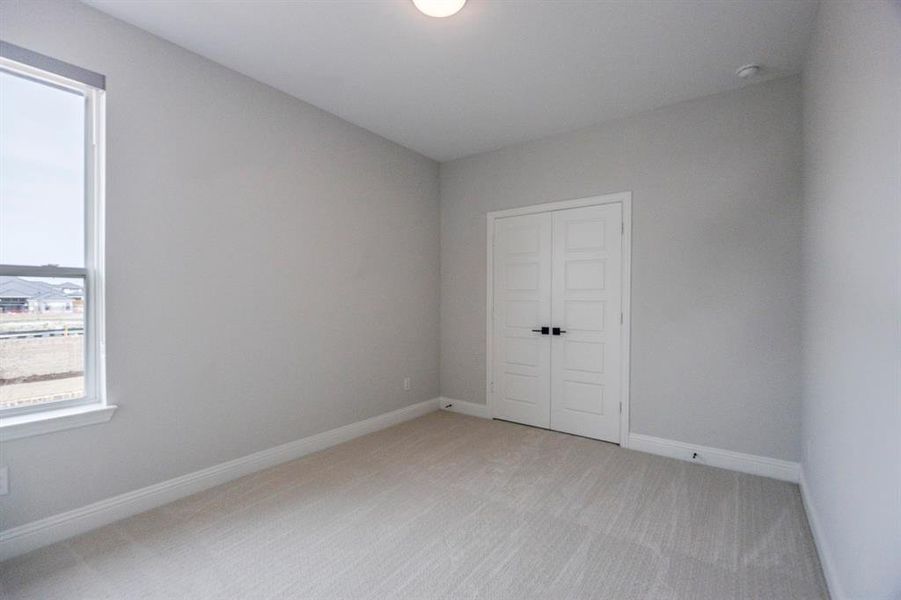 Empty room with light colored carpet and baseboards