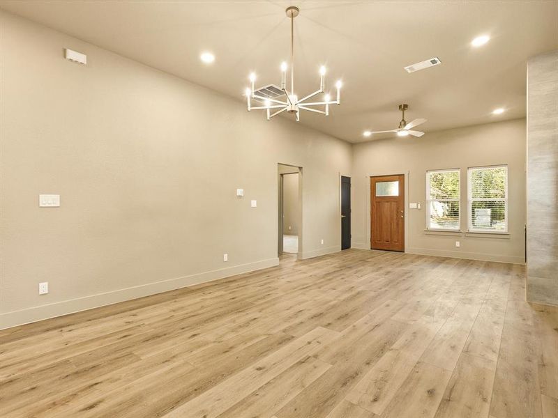 Unfurnished living room with light wood finished floors, recessed lighting, a chandelier, and ceiling fan