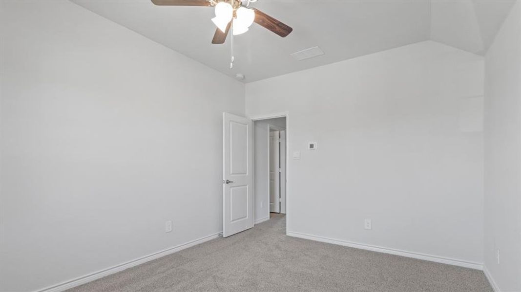 Carpeted empty room featuring a ceiling fan and lofted ceiling