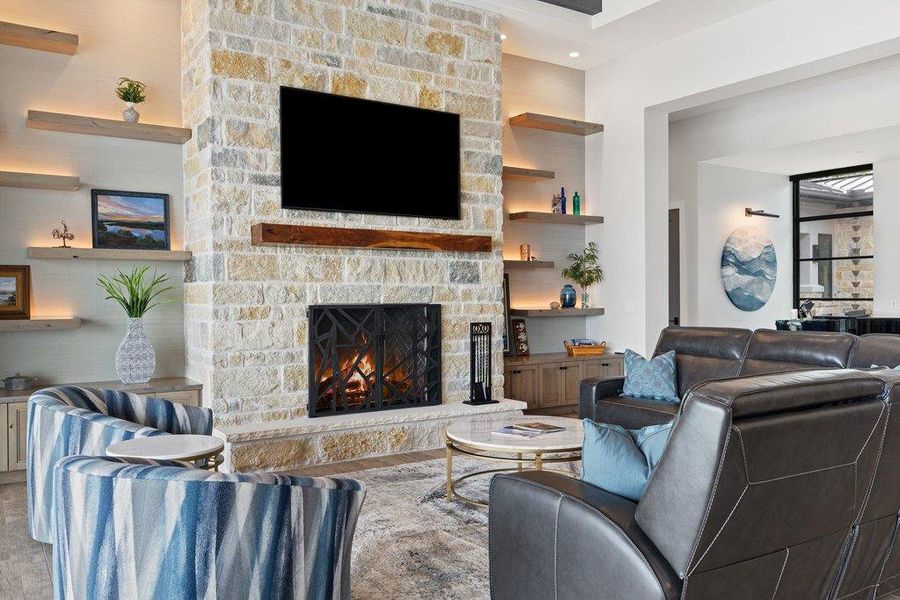 The living room is centered around a floor-to-ceiling stone fireplace with a rustic wood mantle, flanked by custom floating shelves with integrated accent lighting.