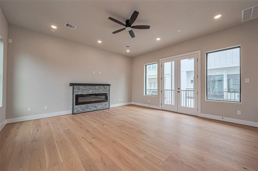 Experience the elegance of this bright, modern living space featuring light wood flooring, neutral tones, and abundant natural light from expansive windows and glass doors. Enhanced with recessed lighting, a ceiling fan, and a chic staircase to the upper level.
