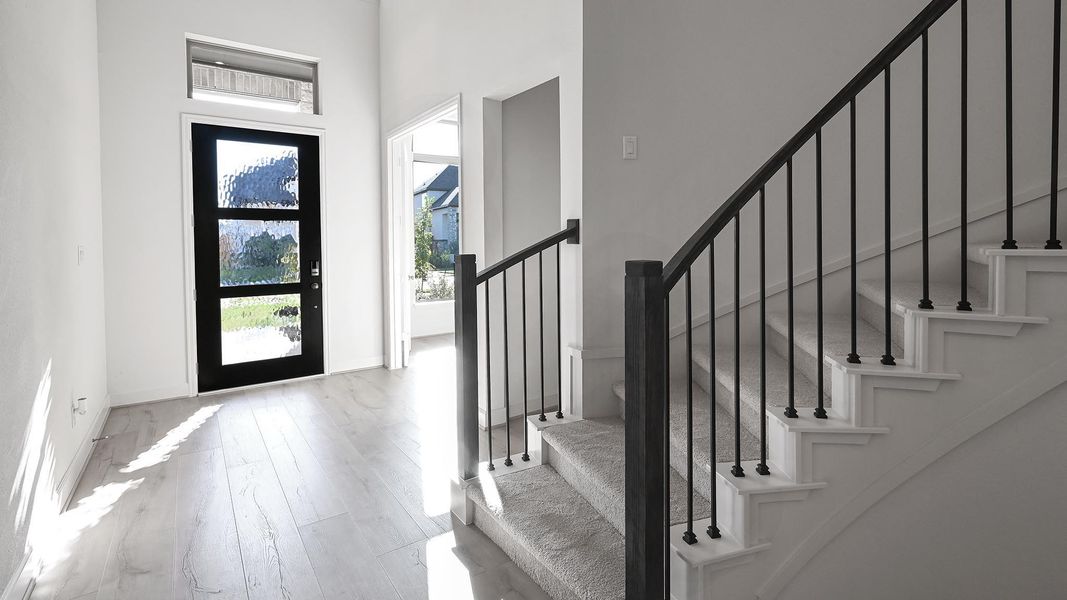 Entryway with stairs, light wood finished floors, and a towering ceiling Entryway with stairs, light wood finished floors, and a towering ceiling