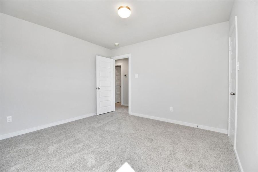 Generously sized secondary bedrooms featuring spacious closets, soft and inviting carpeting underfoot, large windows allowing plenty of natural light. Sample photo of completed home with similar floor plan. As-built interior colors and selections may vary.