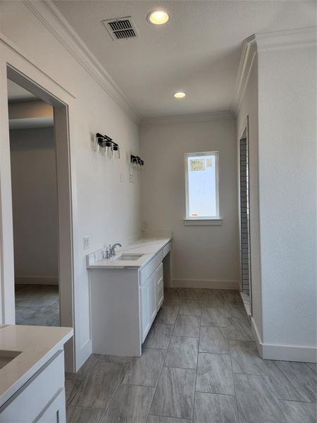 Master Bathroom with Seperate His and Hers vanities, tile patterned floors, and crown molding. View From Master Closet.