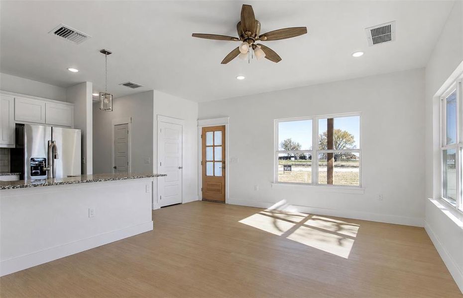 Open-concept living space with light wood-finish flooring, recessed lighting, and a ceiling fan Open-concept living space with light wood-finish flooring, recessed lighting, and a ceiling fan
