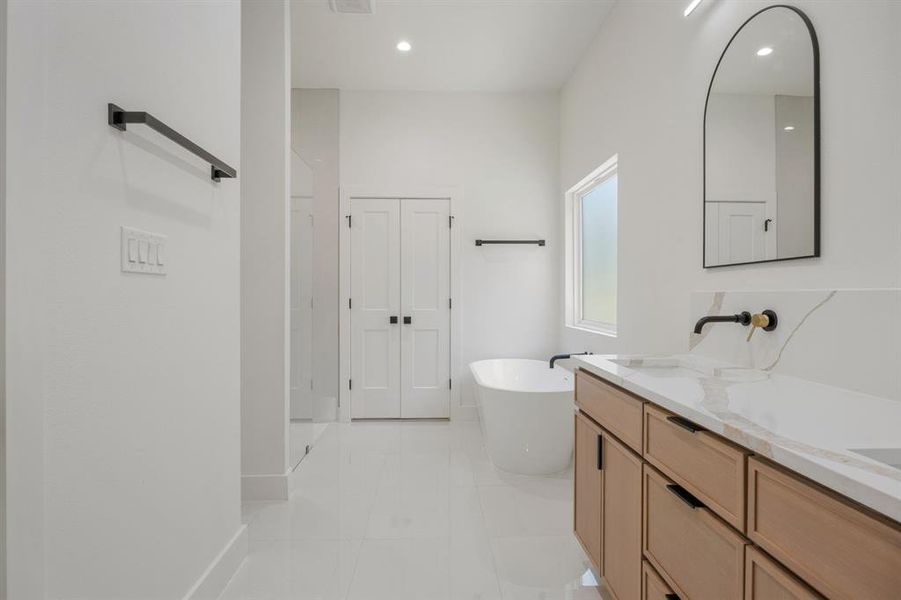 The primary bathroom offers a spa-like experience with dual sinks set within a quartz countertop vanity, a relaxing soaking tub, an oversized separate walk-in shower, and a large window that fills the space with beautiful natural light. The primary bathroom offers a spa-like experience with dual sinks set within a quartz countertop vanity, a relaxing soaking tub, an oversized separate walk-in shower, and a large window that fills the space with beautiful natural light.