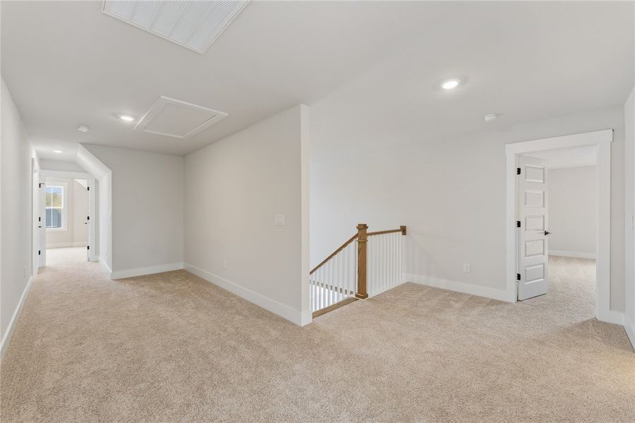 This carpeted loft space features recessed lightin