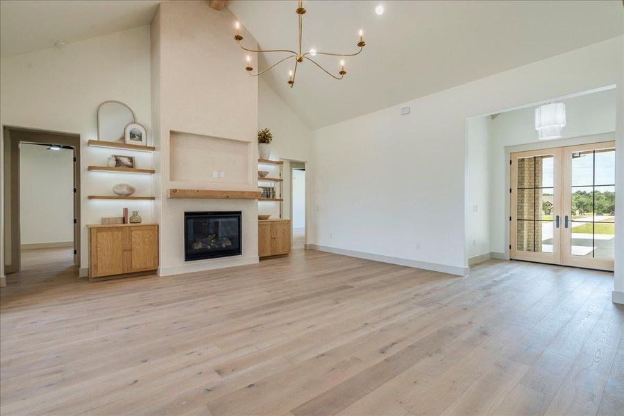 An inviting open-concept living space features light-toned hardwood flooring and an elegant fireplace.