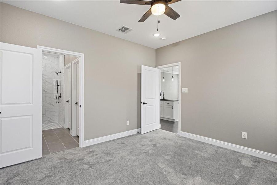 Primary bedroom featuring carpet, ceiling fan, sink, and ensuite bath