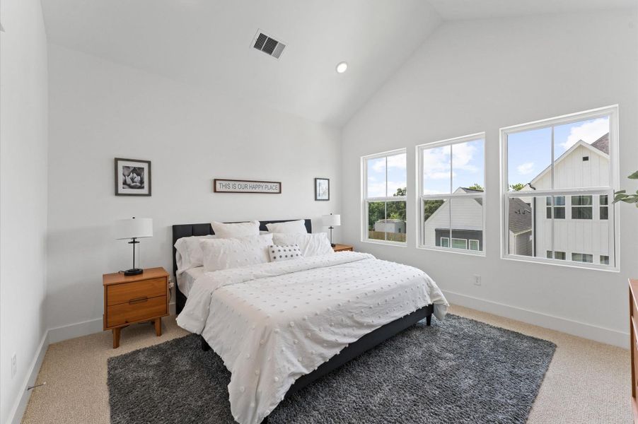 Retreat to the luxurious primary bedroom where soaring ceilings and expansive windows create an airy, light-filled sanctuary.