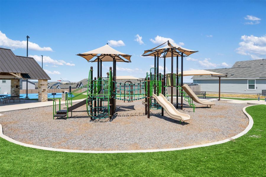 A modern community playground features multiple slides and shade structures under a clear blue sky. A modern community playground features multiple slides and shade structures under a clear blue sky.