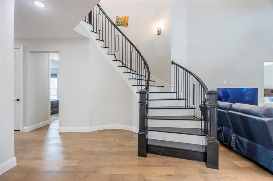 Stairway featuring a towering ceiling, recessed lighting, baseboards, and wood finished floors