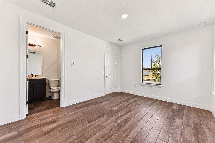 Unfurnished bedroom featuring wood finished floors, ensuite bath, and recessed lighting