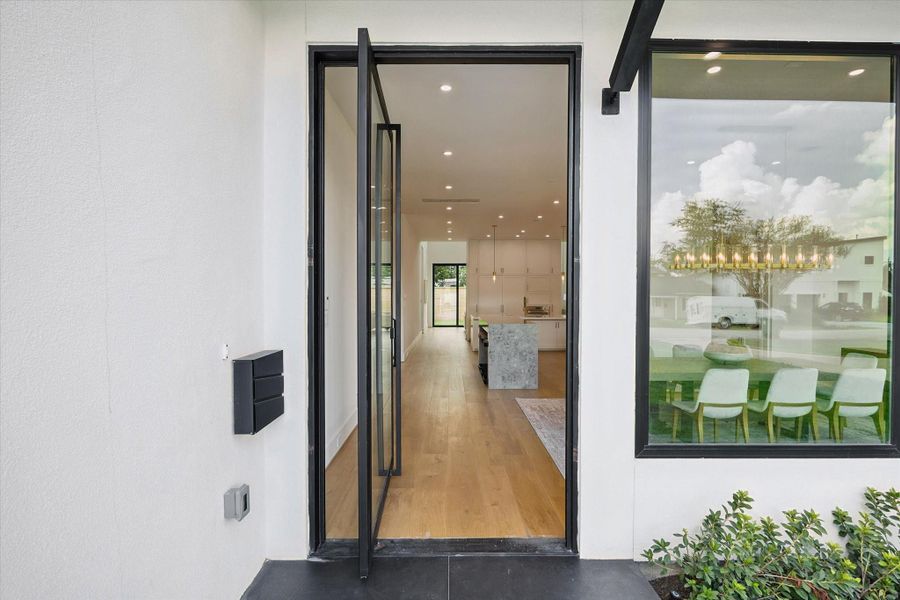 Modern entryway with glass pivot door leading to the foyer and living areas. Modern entryway with glass pivot door leading to the foyer and living areas.