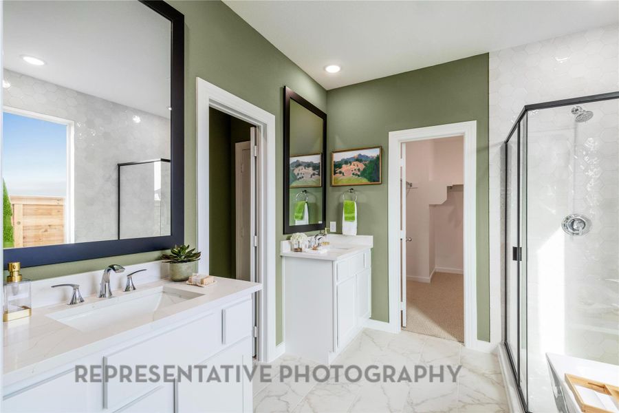 Full bathroom featuring a stall shower, two vanities, marble finish flooring, and a spacious closet