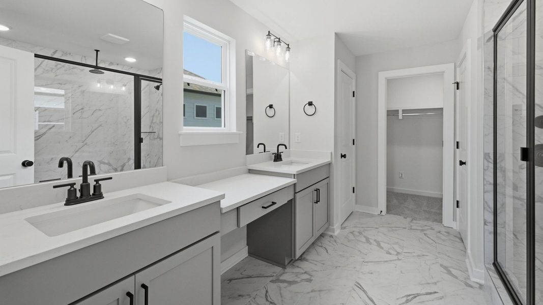 Primary bathroom with dual vanity, glass enclosed shower, and access to closet