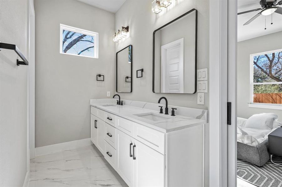 Bathroom with marble finish floor, double vanity, a sink, and baseboards