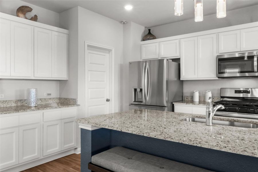 Kitchen with white cabinetry, appliances with stainless steel finishes, light stone countertops, dark wood-style floors, and recessed lighting