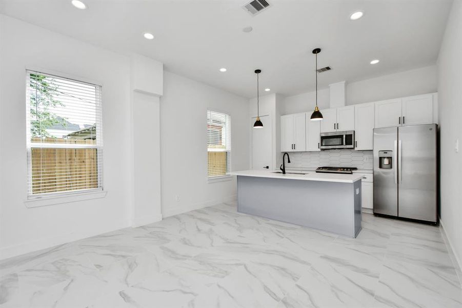 Discover culinary delights in this modern kitchen equipped with warm and elegant light fixtures, stainless steel appliances that elevate your cooking experience.