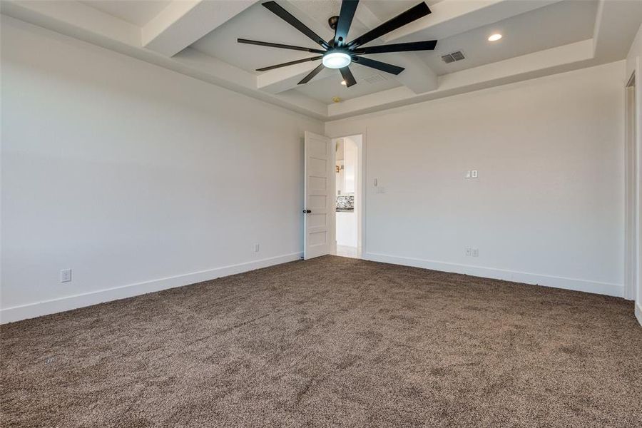 Empty room with carpet floors, a tray ceiling, and ceiling fan