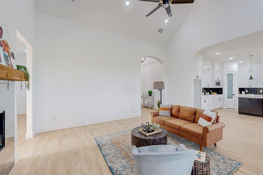 Living room with ceiling fan, light hardwood / wood-style flooring, and high vaulted ceiling