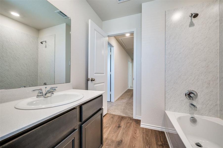 Bathroom with vanity, hardwood / wood-style floors, and tiled shower / bath combo