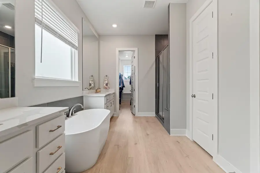 Full bathroom featuring vanity, a soaking tub, a stall shower, light wood finished floors, and recessed lighting Full bathroom featuring vanity, a soaking tub, a stall shower, light wood finished floors, and recessed lighting