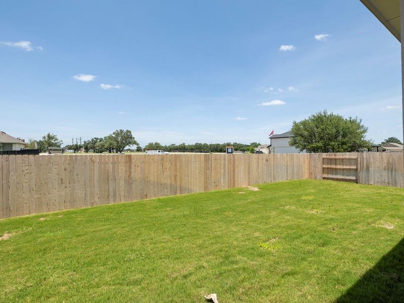 A well-maintained lawn provides ample space for outdoor activities, enclosed by a privacy fence.