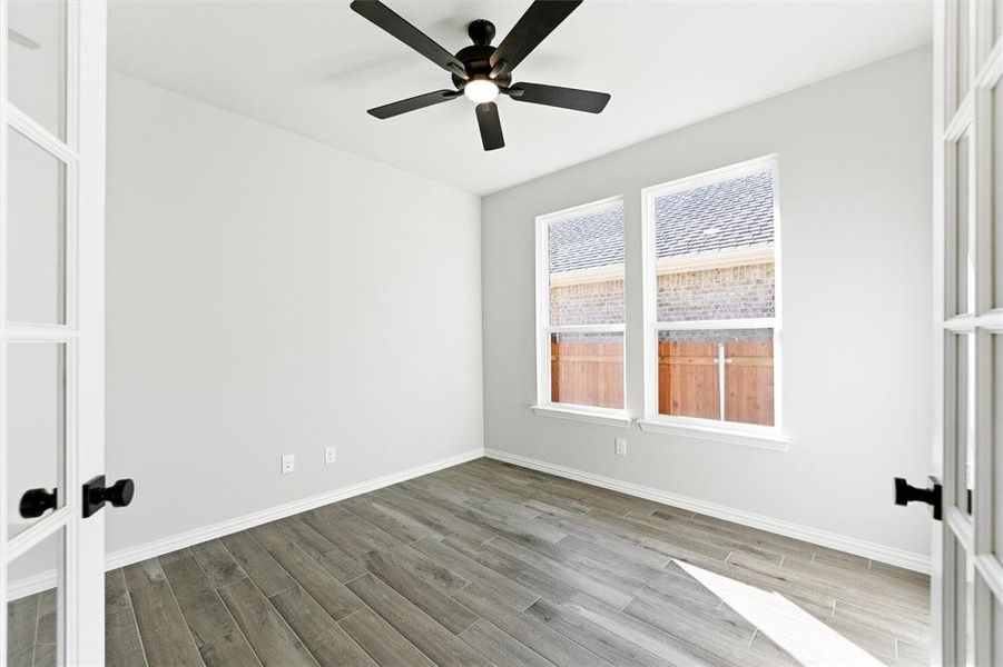 Empty room featuring wood finish floors, french doors, and ceiling fan