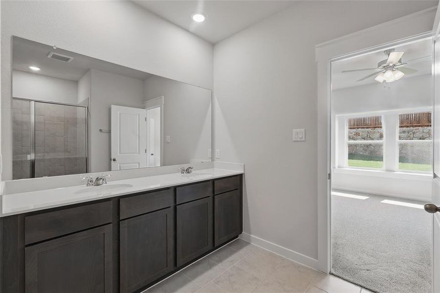 Bathroom with double vanity, ceiling fan, a stall shower, light carpet, and light tile patterned floors