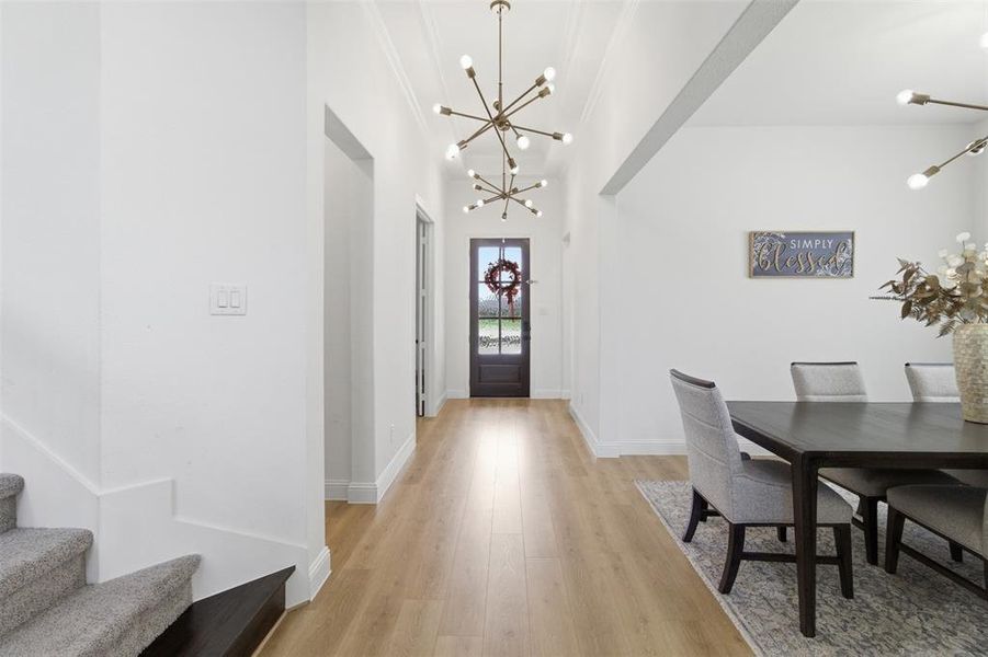 Entryway featuring light wood-finish flooring, white walls, and contemporary sputnik chandeliers