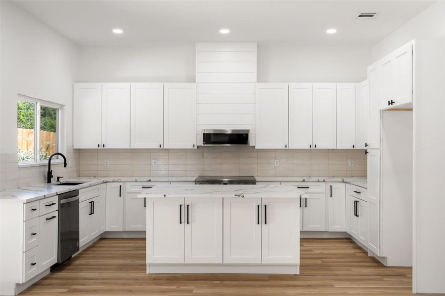 Kitchen featuring white cabinetry, a kitchen island, light wood-style flooring, decorative backsplash, and recessed lighting Kitchen featuring white cabinetry, a kitchen island, light wood-style flooring, decorative backsplash, and recessed lighting