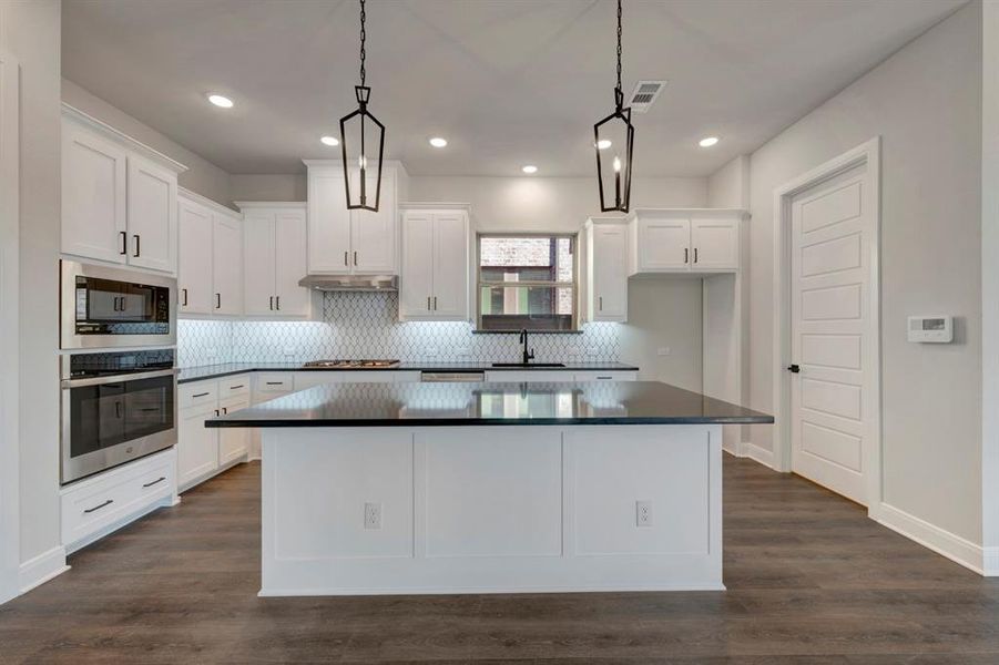Kitchen featuring stainless steel appliances, a kitchen island, white cabinets, tasteful backsplash, and dark wood-style floors