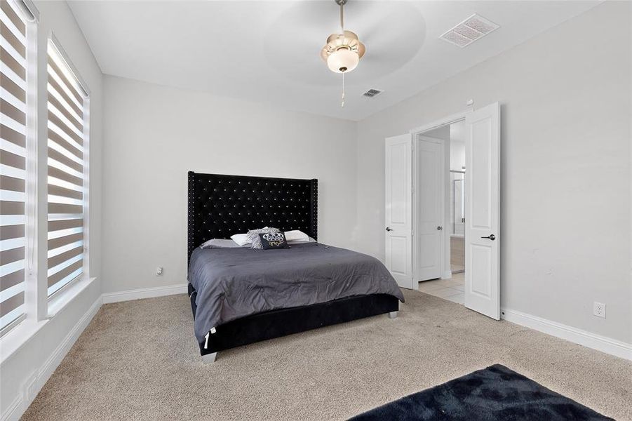 Bedroom with light colored carpet and a ceiling fan