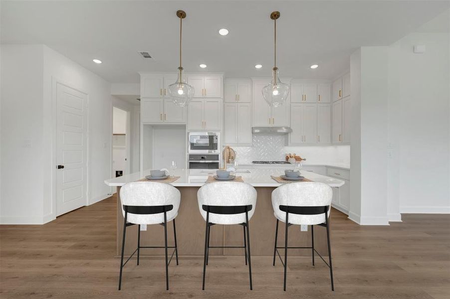 Kitchen featuring a central island with countertop seating, white shaker cabinetry, stainless steel appliances, and wood-finish flooring