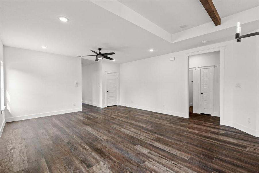 Empty room featuring ceiling fan, dark hardwood / wood-style flooring, and beamed ceiling