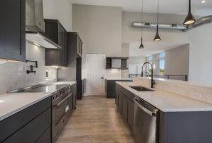 Kitchen with a sink, stainless steel appliances, light wood-style floors, light countertops, and hanging light fixtures