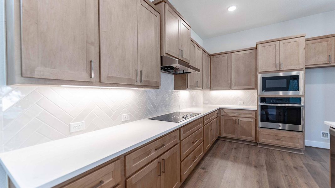 Kitchen featuring appliances with stainless steel finishes, backsplash, dark wood-type flooring, under cabinet range hood, and recessed lighting Kitchen featuring appliances with stainless steel finishes, backsplash, dark wood-type flooring, under cabinet range hood, and recessed lighting