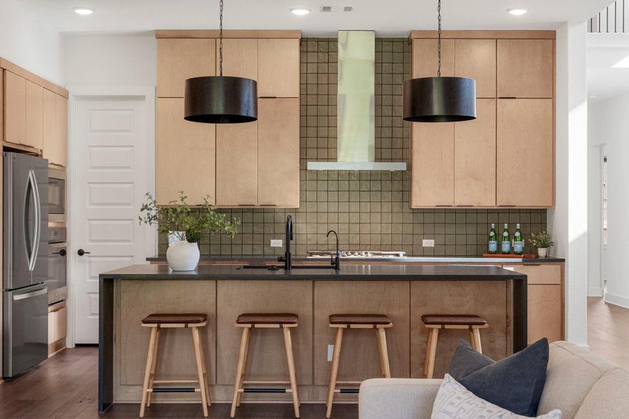 A contemporary chef's kitchen features a central island with bar seating and sleek, modern fixtures.