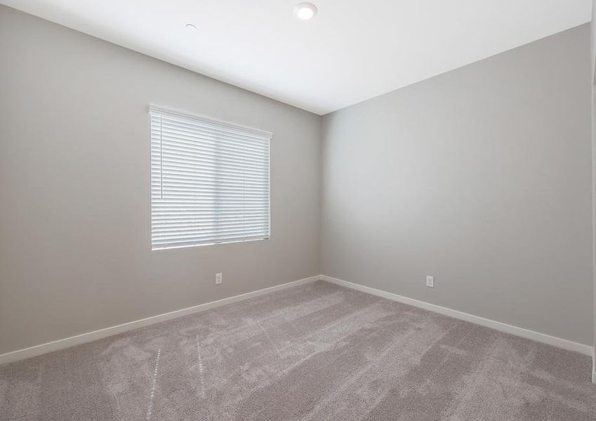 Secondary bedroom with a window with faux wood blinds.