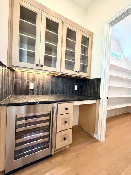 A refined dry bar with a built-in wine refrigerator and glass-front cabinetry offers elegant entertaining. A refined dry bar with a built-in wine refrigerator and glass-front cabinetry offers elegant entertaining.