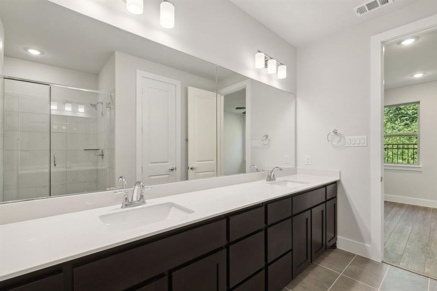 Full primary bath with double vanity, a stall shower, visible vents, and a sink