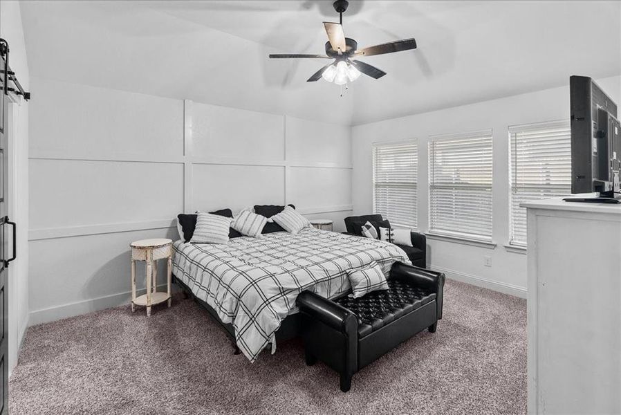 Bedroom with a decorative wall, carpet flooring, a ceiling fan, and baseboards