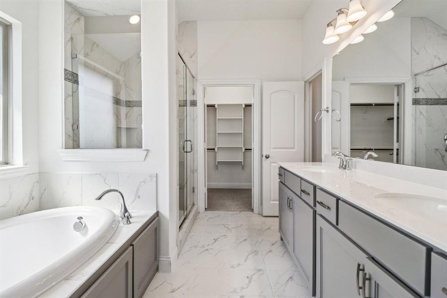 Bathroom with a walk in closet, a marble finish shower, a bath, double vanity, and light marble finish floors Bathroom with a walk in closet, a marble finish shower, a bath, double vanity, and light marble finish floors