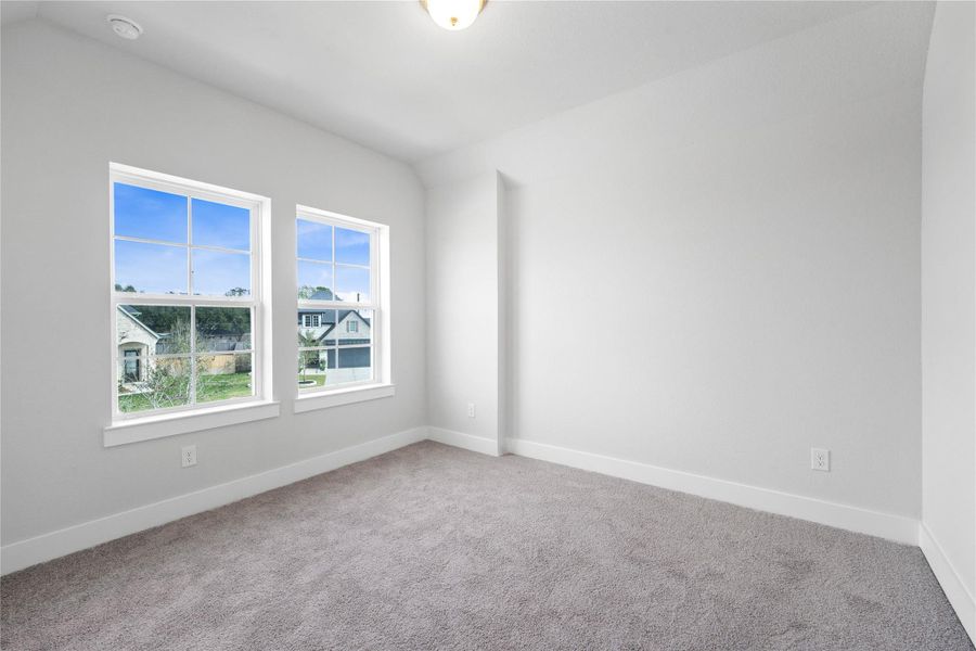 This inviting secondary bedroom combines comfort and modern elegance, featuring a soft neutral color palette, sleek design elements, and abundant natural light streaming through large windows.